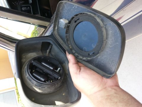 1994 Ford Bronco - The internal components of a car's side mirror assembly are exposed as the housing is removed.