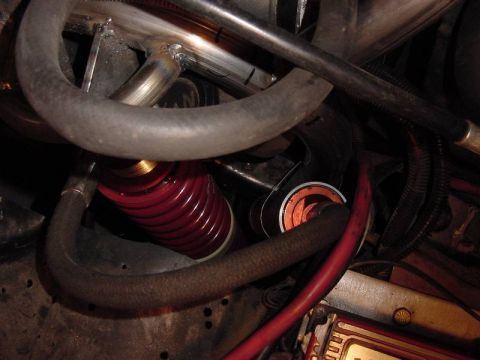 1987 Ford Bronco - This image shows a close-up view of various engine bay components, including hoses and a red coilover shock absorber.
