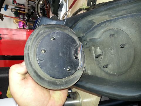 1994 Ford Bronco - Close-up of a vehicle's fuel filler neck assembly being held by a hand, showing wires and mounting points.