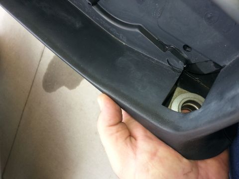 1994 Ford Bronco - A close-up of a car's interior trim piece with a visible metal component and a water stain on the floor.