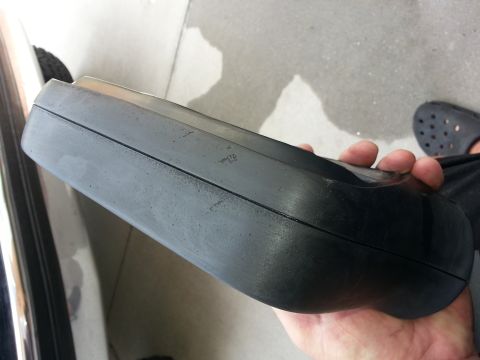 1994 Ford Bronco - A person holds a black plastic automotive part, possibly an interior trim piece or exterior component.