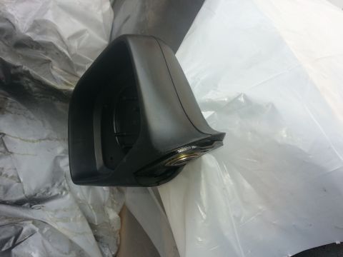 1994 Ford Bronco - A black side mirror housing is shown, with its internal components exposed and resting on white plastic sheeting.