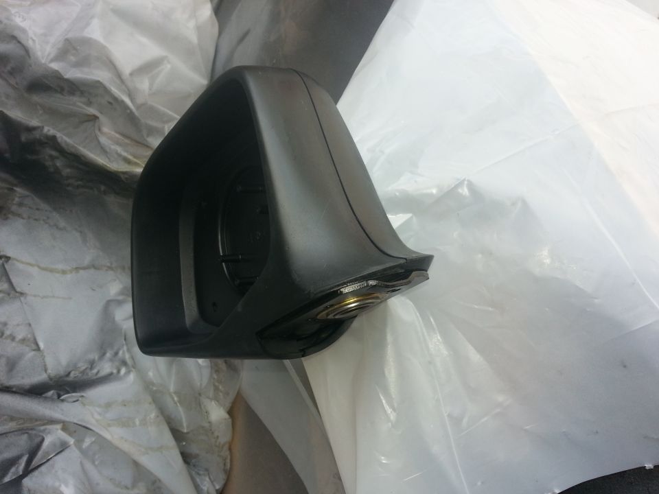 Black side mirror housing with visible internal mechanism, resting on white plastic