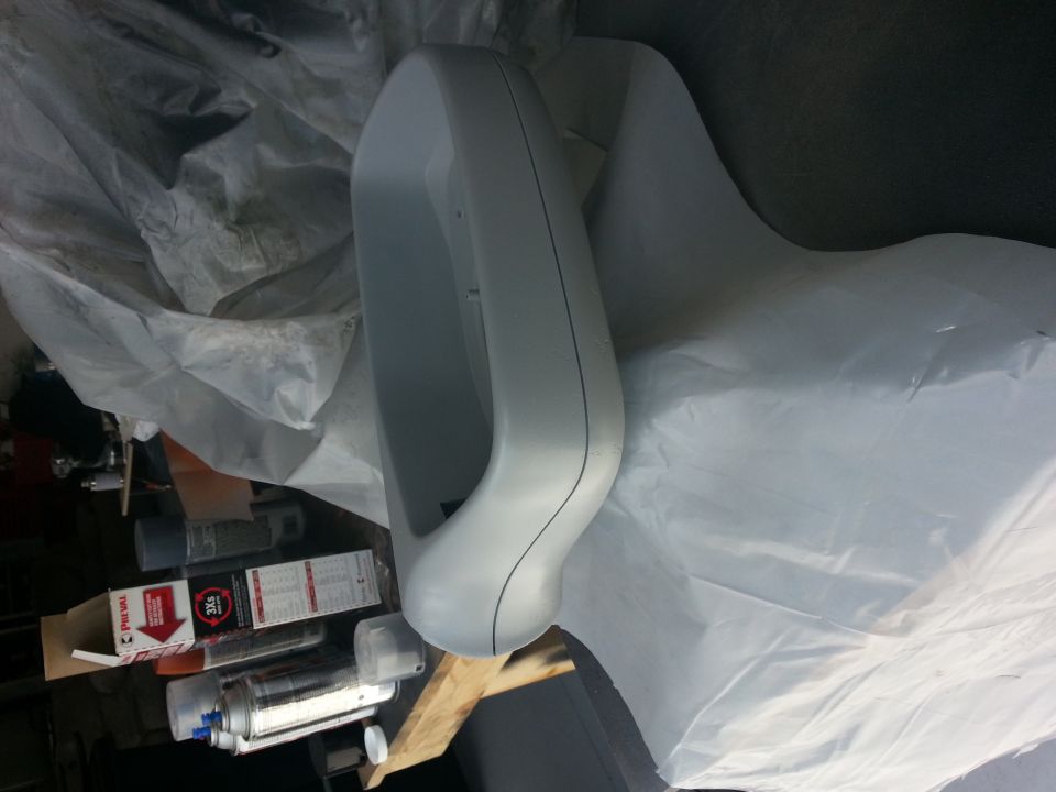 Gray plastic car part, possibly a bumper or fender, covered in plastic sheeting