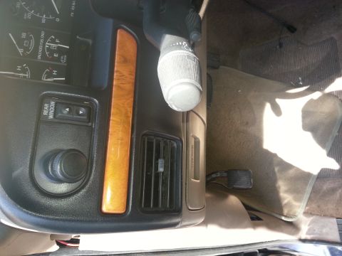 1994 Ford Bronco - Dashboard view showing gauges, wood grain trim, and a rear window control.