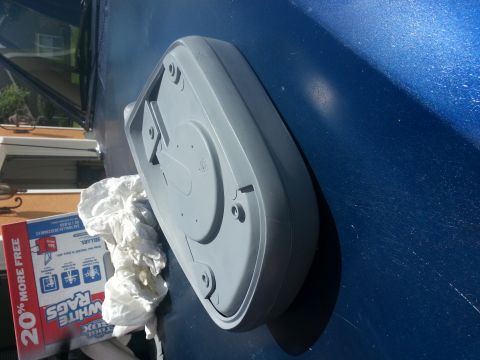 1994 Ford Bronco - A gray plastic part is shown on the hood of a blue vehicle, with a box of rags to the side.