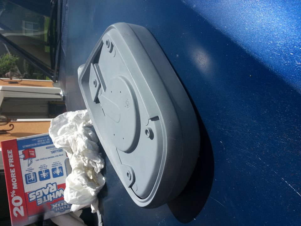gray plastic part on blue vehicle hood, box of rags nearby