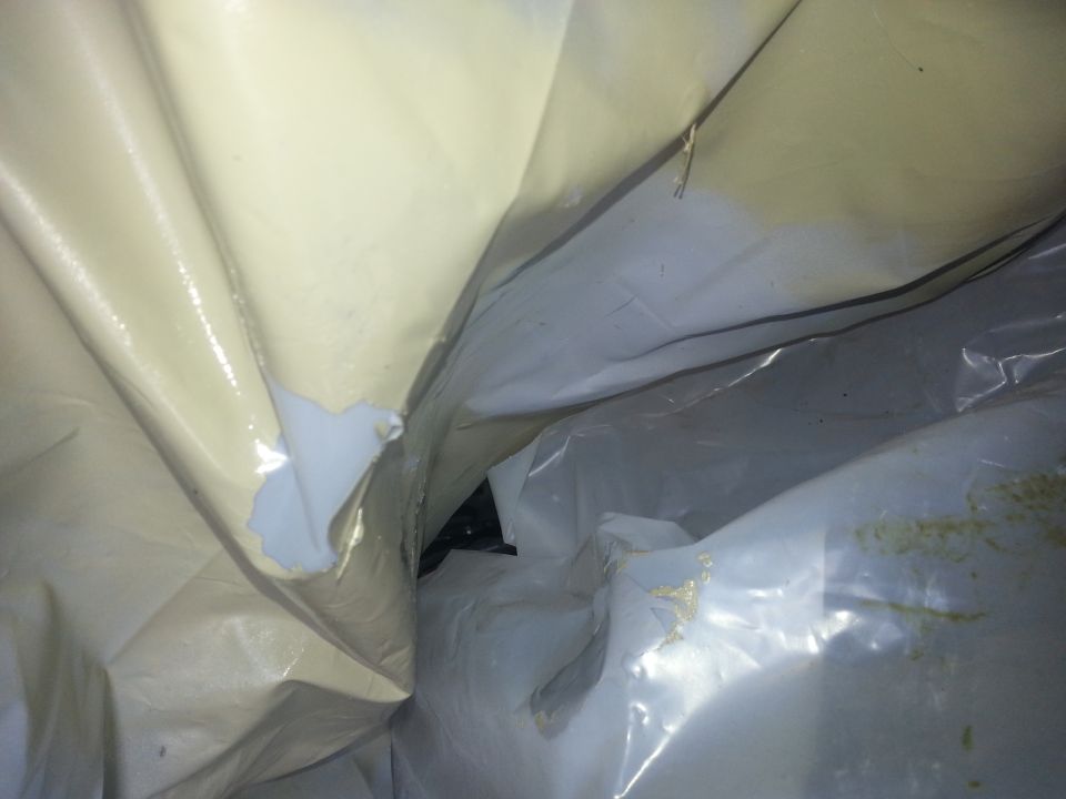 Inside of a torn car cover, showing some of the vehicle underneath
