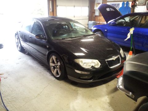 2002 Chrysler 300M - A black Chrysler 300M is parked in a garage, with another vehicle's hood open in the background.
