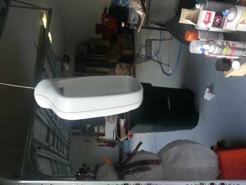 1994 Ford Bronco - Unidentified white plastic part in a garage, surrounded by various items and equipment.