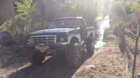 1994 Ford Bronco - Modified Ford F-Series truck with off-road tires navigates a muddy path.