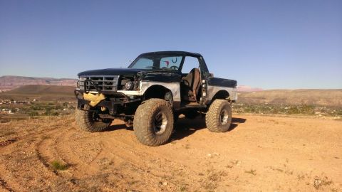 1994 Ford Bronco - This modified 1994 Ford Bronco sits on a dirt hill under a clear blue sky, its off-road capabilities.