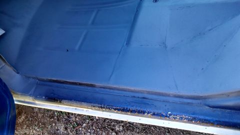 1979 Ford Bronco - The interior floor of a vehicle shows a blue painted surface with distinct seams and a dark seal at the door sill.
