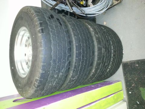 1994 Ford Bronco - A set of four tires, each with a silver rim, are stacked and ready for use.