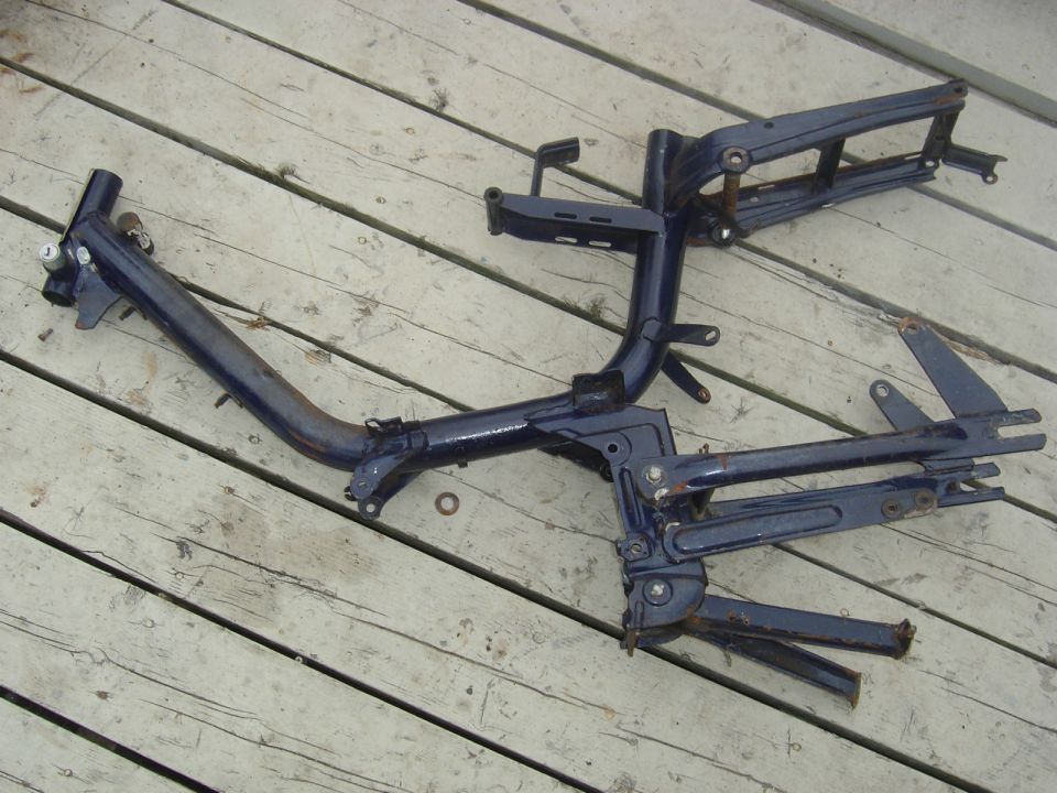 Dark blue moped frame on wooden planks. Some rust visible