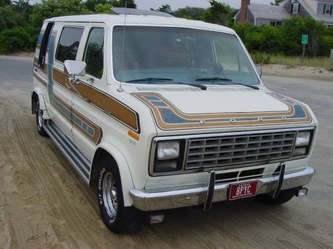 1981 Ford E150 - This 1981 Ford E150 van features a distinctive stripe package and is parked on a sandy surface.