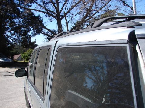 1973 Ford Ranchero - The side profile of an SUV is captured, with reflections of trees and sky visible in the tinted windows.