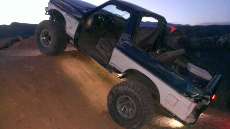 1994 Ford Bronco with doors open, tilted on a dirt hill