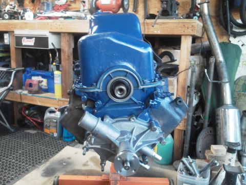 1988 Ford Bronco - A blue engine assembly, likely a Ford V8, is displayed on an engine stand in a cluttered garage setting.