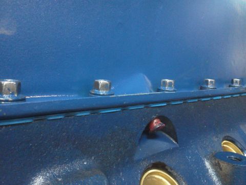 1988 Ford Bronco - Close-up view of a blue engine block, showing hex bolts and internal oil passages.