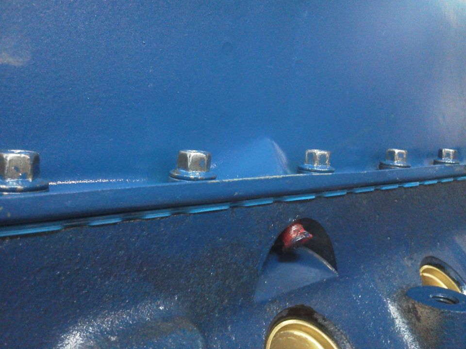 Blue engine block with hex bolts and oil passages