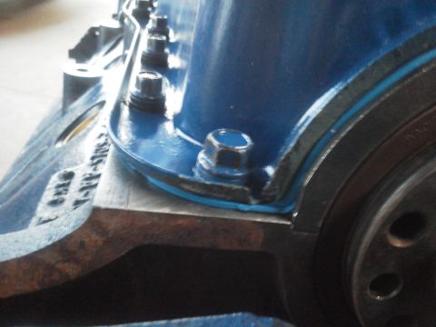 1988 Ford Bronco - A close-up view of a blue painted engine block component, showing bolts and a metal flange.