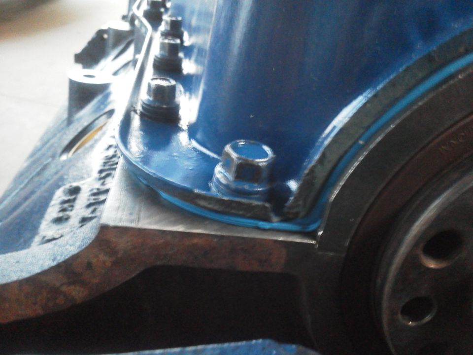 Close-up of blue painted engine block with bolts and a metal flange