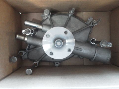 1988 Ford Bronco - A metal engine water pump with a silver flange and two pipes is shown in a cardboard box.