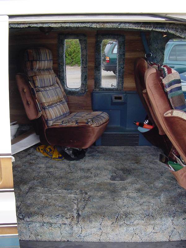 Van interior with brown striped swivel captain's chair, wood paneling, and blue-gray shag carpet.