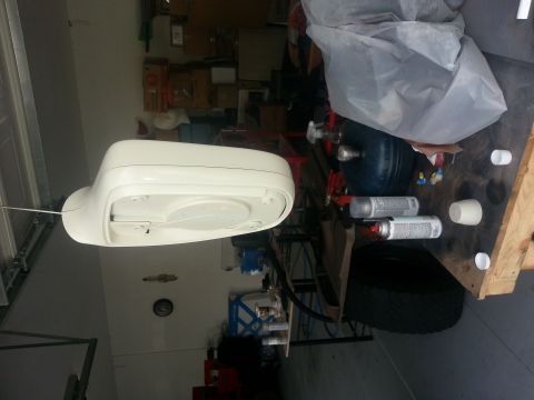 1994 Ford Bronco - A detached white car side mirror is shown in a workshop setting with various tools and supplies.