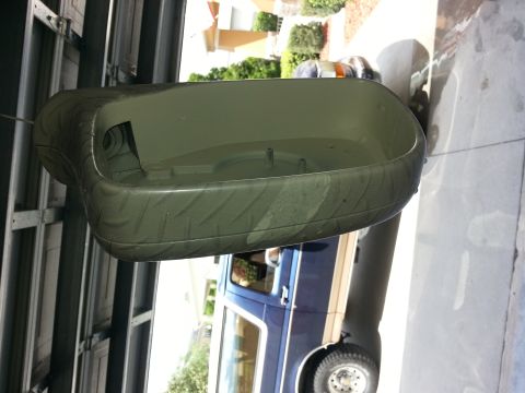 1994 Ford Bronco - A green plastic part with a tire tread pattern is shown, with a blue vehicle in the background.