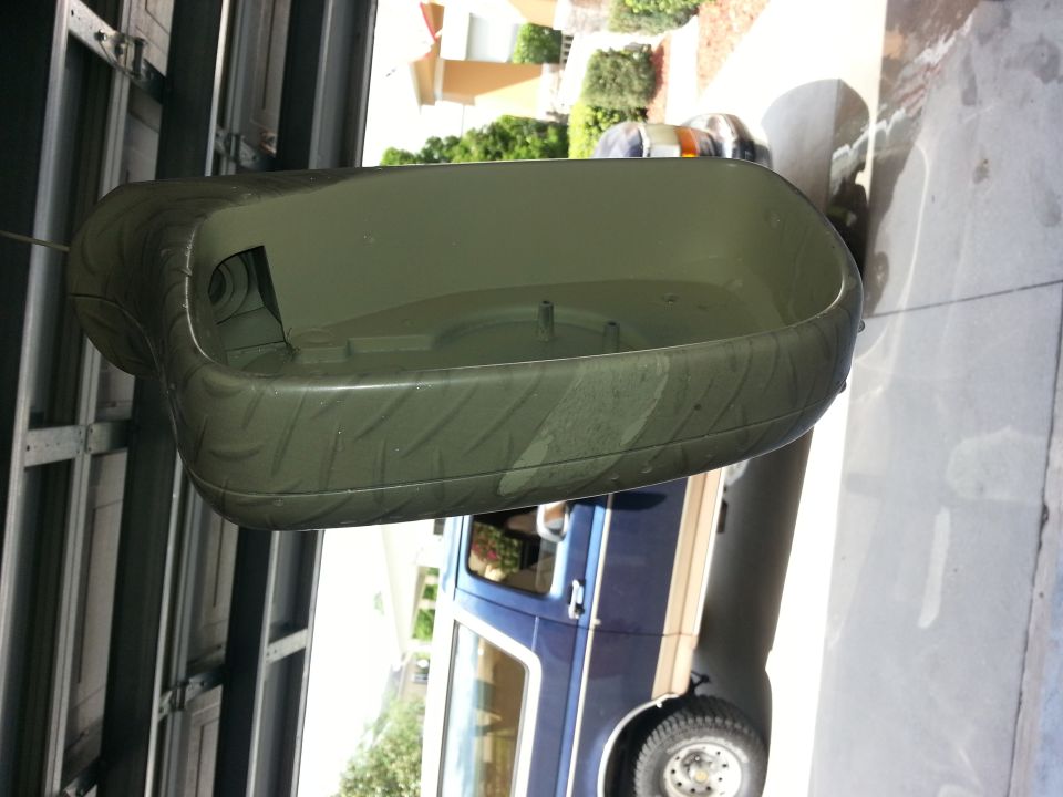 green plastic part with tire tread pattern, sitting in front of a blue vehicle