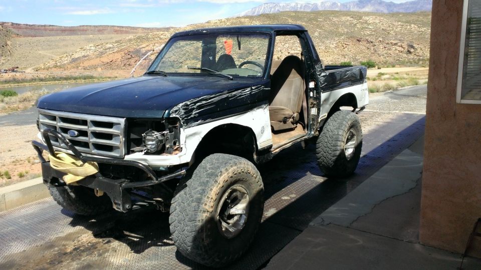 Front 3/4 view of a damaged 1994 Ford Bronco with black and white paint