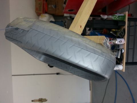 1994 Ford Bronco - A car fender with a diamond-plate texture is held by wooden beams, suggesting it's being worked on or displayed.