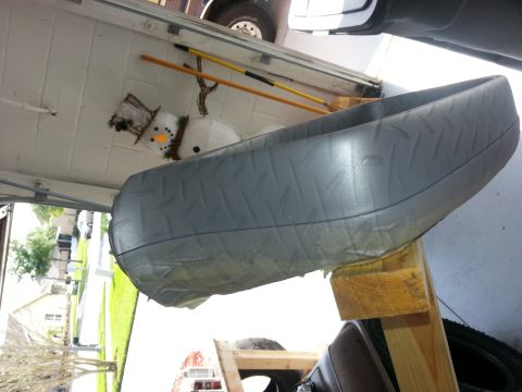 1994 Ford Bronco - A gray plastic part, possibly a bumper or fender, is supported by wooden beams in a garage. A snowman decoration and brooms are visible in…