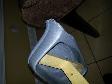 1994 Ford Bronco - A gray plastic part, possibly a fender liner or trim piece, is supported by a wooden brace. The Supermotors logo is visible in the lower ri…