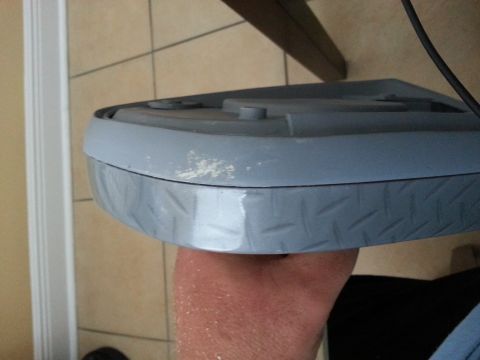 1994 Ford Bronco - Close-up of a gray automotive part with a textured lower edge, held by a person's hand.