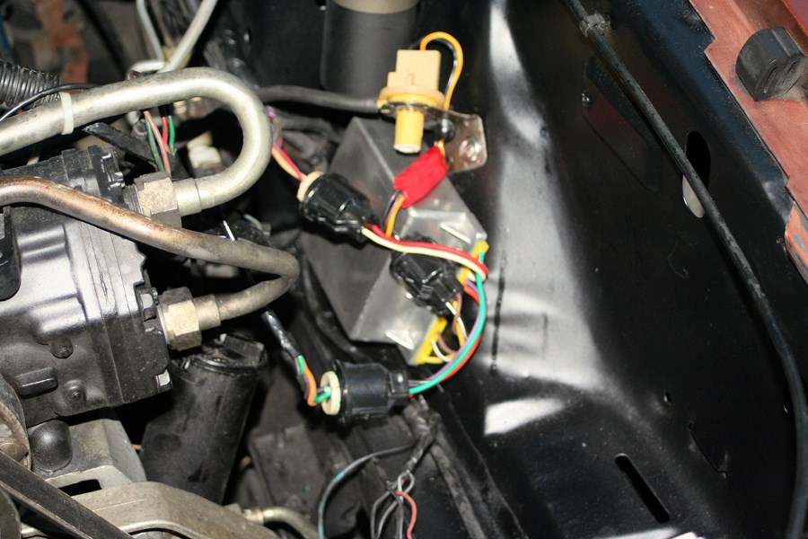 Close-up of vehicle wiring harness and electrical components in engine bay