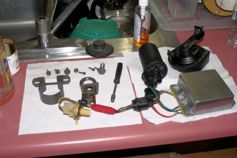 1980 Ford Mustang - Several automotive electrical components and hardware are laid out on a counter next to a sink.