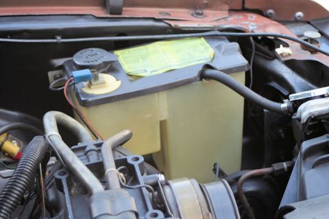 1980 Ford Mustang - Close-up of a vehicle's windshield washer fluid reservoir and associated hoses.