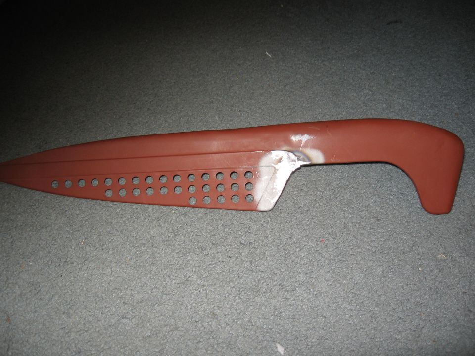 brown car door handle with rows of circular holes and a metal repair patch