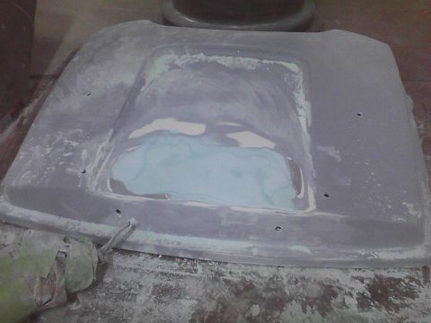 2003 Ford Crown Victoria - A car hood is being repaired with body filler and sanding.