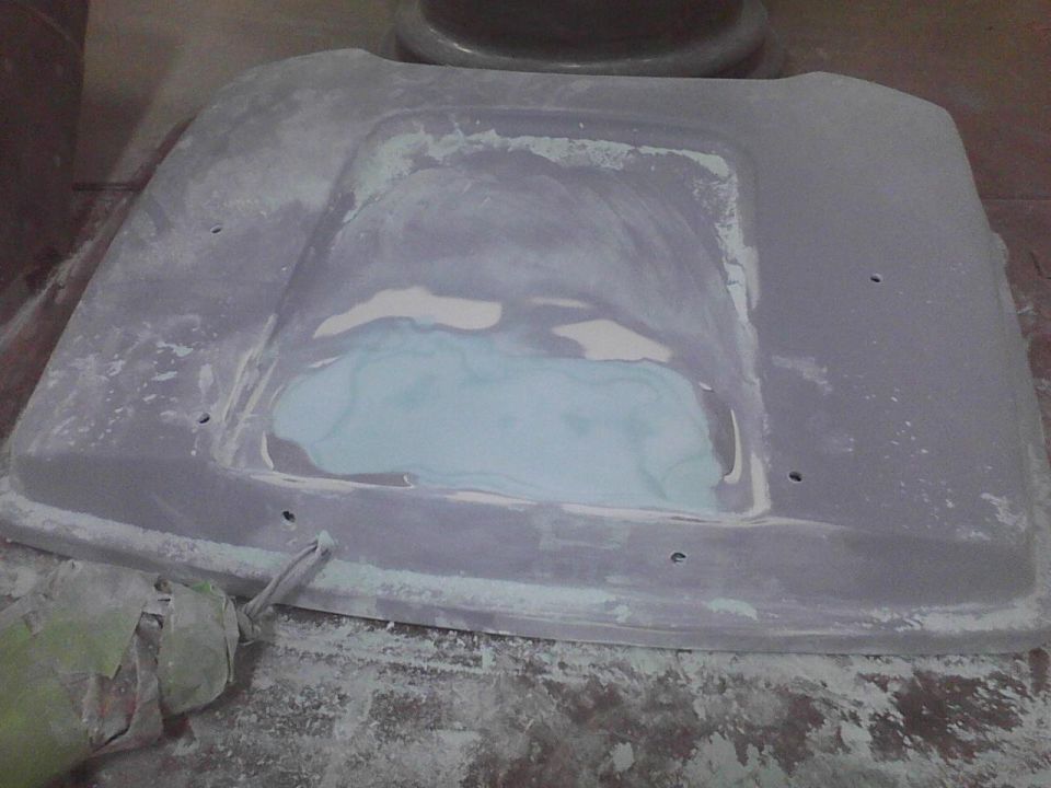 Gray car hood with body filler and sanding dust, viewed from above