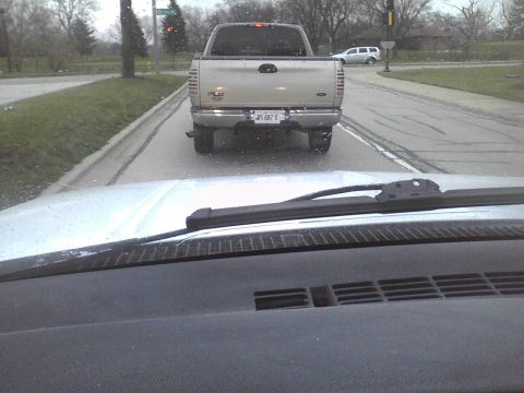 2003 Ford Crown Victoria - A silver pickup truck is seen from behind on a wet road, with another vehicle visible in the distance.