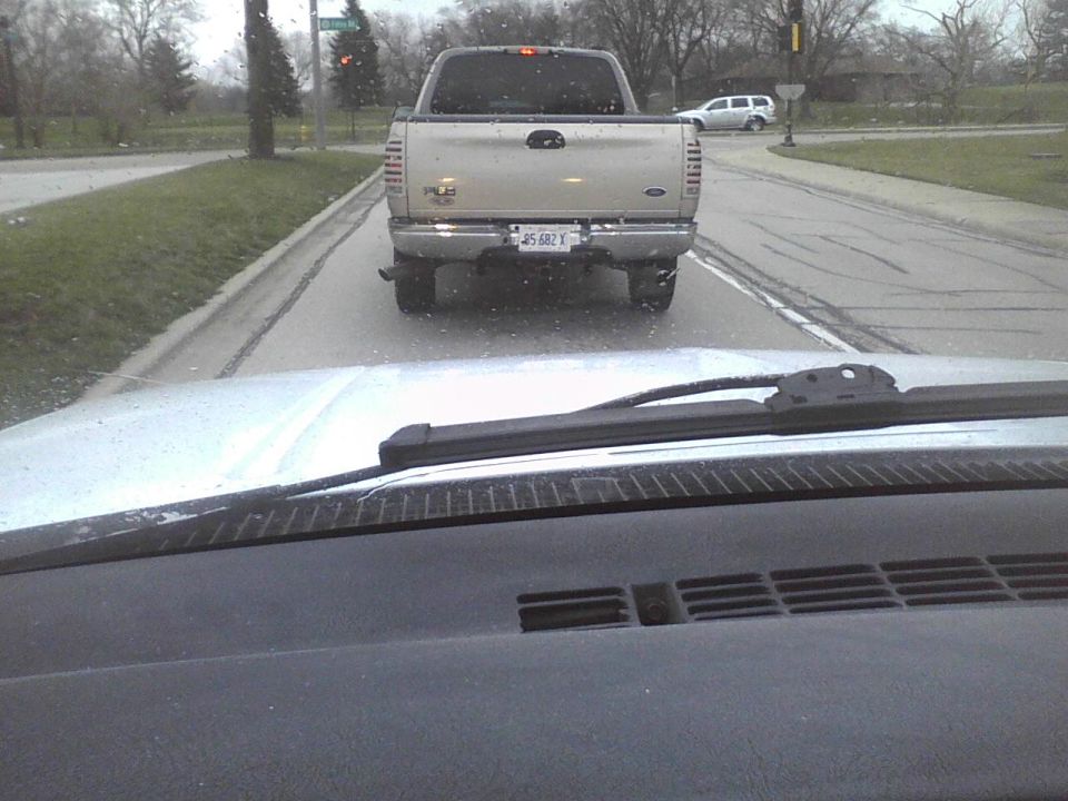 Rear view of silver pickup truck with license plate J5 682 X
