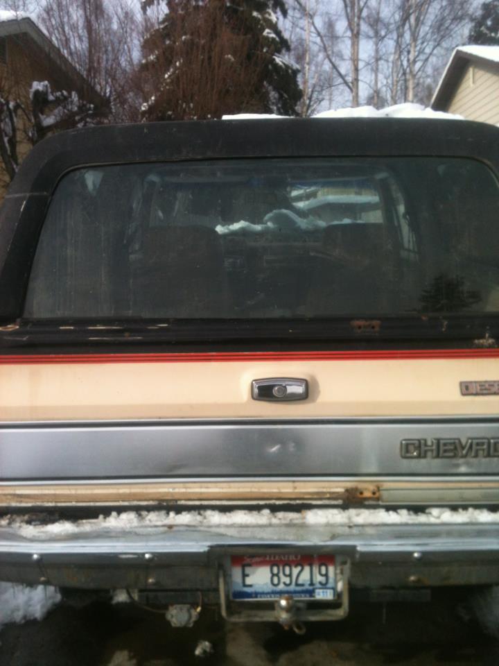 Rear of a two-tone Chevrolet pickup truck with a black camper shell, showing a license plate and a 'DIESEL' badge