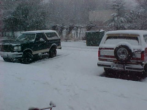 1990 Ford Bronco - Two 1990 Ford Broncos are parked outside during a snowfall.