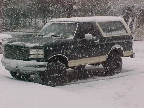 1990 Ford Bronco - A black Ford Bronco sits in a snowy landscape during a snowfall.
