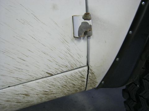 1970 Ford Bronco - Mud splatters are visible on the side of a white vehicle, near the door hinge and fender flare.