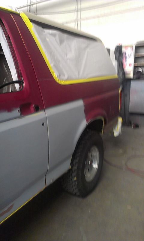 1994 Ford Bronco - SUV in a repair shop, masked for painting, showing primer on the lower body panels.